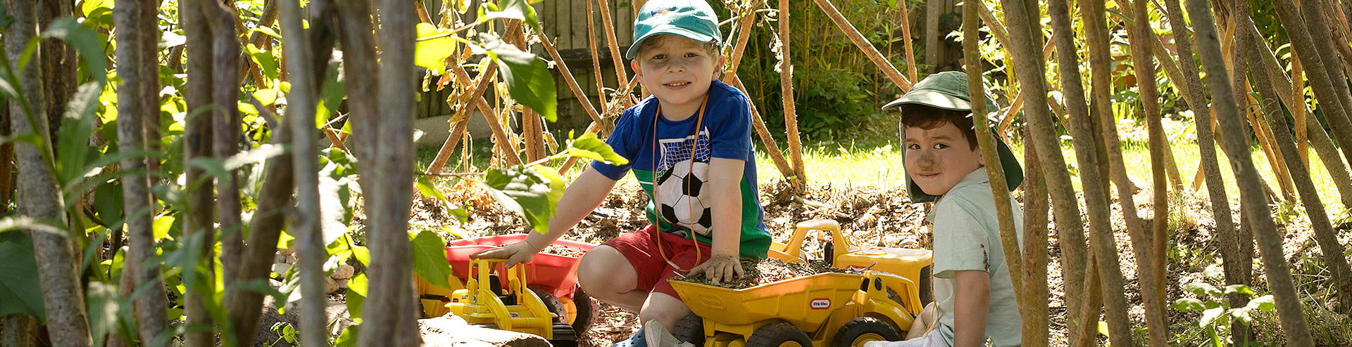Two boys playing with diggers in Jigsaw garden